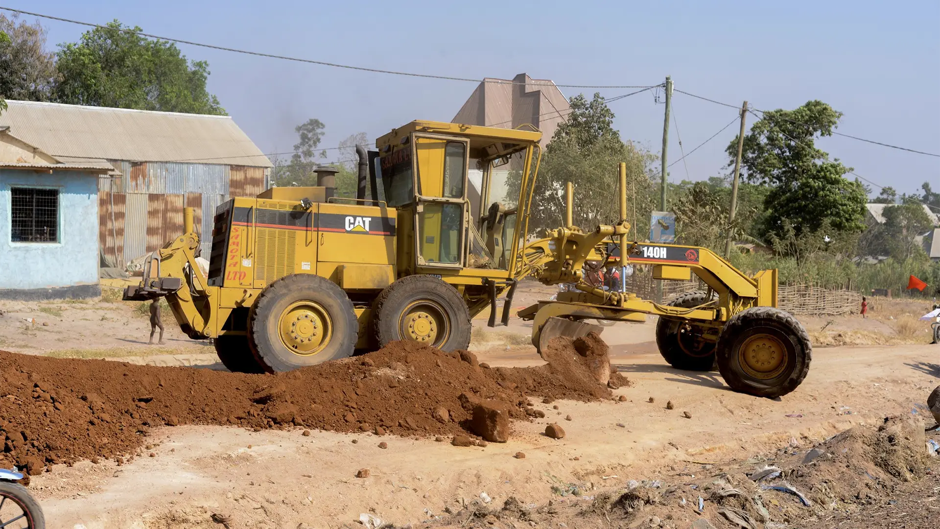 A grader shapes quality laterite road material during repairs on the Katoro to Imwelo access road.